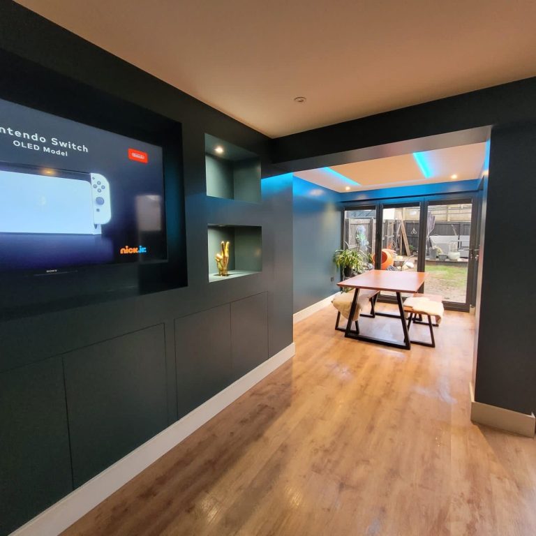 Bespoke MDF Media wall with recessed wall mounted TV, alcove shelving and hidden doors for storage.