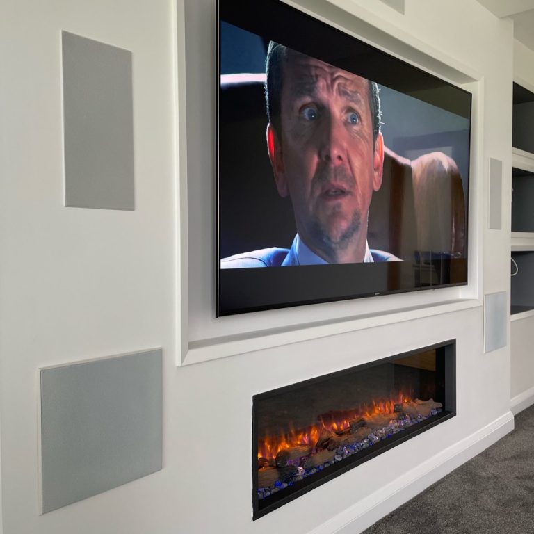 Fireplace media wall with recessed tv, display shelves and a full cinema installation.